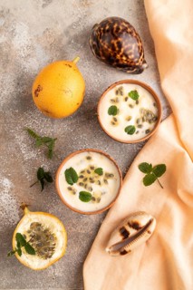 Yoghurt with granadilla and mint in clay bowl on brown concrete background and orange linen textile