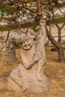 Stone carved statue of Buddhist deity in front of white wall in garden in South Korea