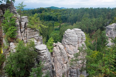 Majestic rock formations rise up in the middle of a dense forest under a cloudy sky, Prachovske