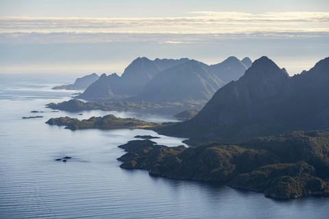 View of the coast in Ulvagsundet fjord and mountains in the evening light, view from the summit of