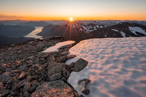 View of mountains and fjord Faleidfjorden, sun star at sunset, summit of Skala, Loen, Norway,