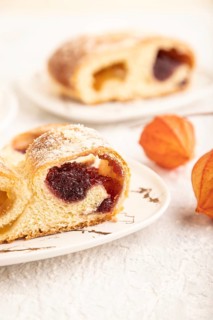 Homemade sweet bun with apricot jam and cup of coffee on gray concrete background. side view, close