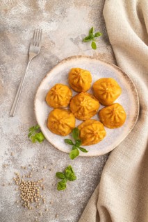 Fried manti dumplings with pepper, basil on gray concrete background and linen textile. Top view,