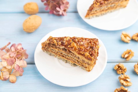 Walnut and hazelnut cake with caramel cream, cup of coffee on blue wooden background. side view,