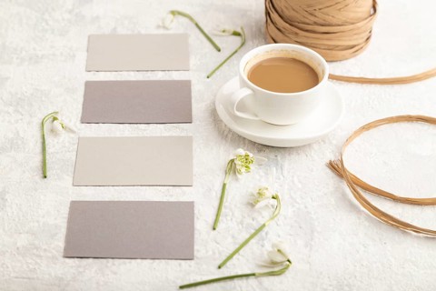 Gray paper business card mockup with spring snowdrop galanthus flowers and cup of coffee on gray