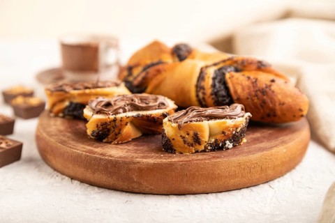 Homemade sweet bun with chocolate cream and cup of coffee on a gray concrete background and linen