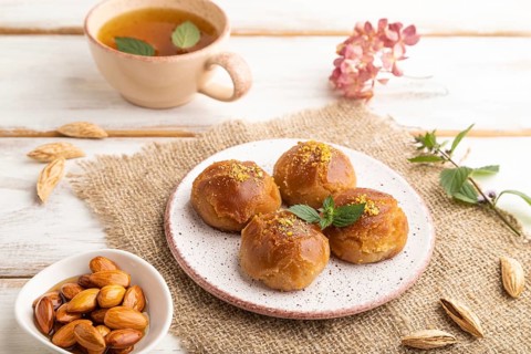 Homemade traditional turkish dessert sekerpare with almonds and honey, cup of green tea on white