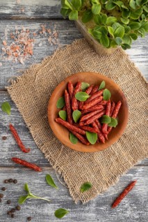 Small smoked sausage with borage microgreen, salt and pepper on gray wooden background and linen