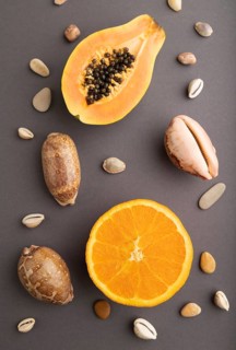 Ripe cut papaya, orange, seashells on gray pastel background. Top view, flat lay, close up.