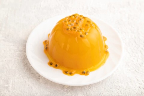 Mango and passion fruit jelly on gray concrete background. side view, close up