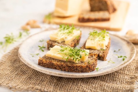 Grain bread sandwiches with cheese and watercress microgreen on gray concrete background and linen