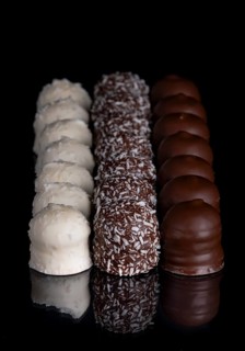 Row of chocolate kisses covered with dark and light chocolate, grated coconut, reflection, dark