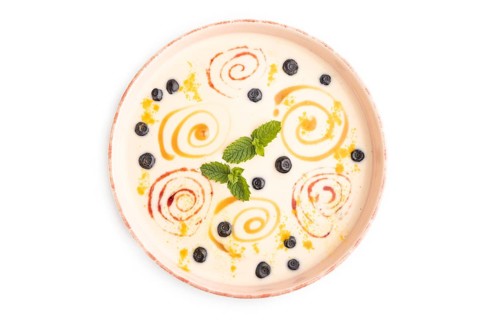 Yoghurt with bilberry and caramel in ceramic bowl isolated on white background. top view, flat lay,