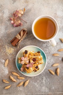 Traditional candy nougat with nuts and sesame with cup of green tea on brown concrete background.
