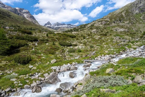 Mountaineer on a bridge over a mountain stream, Hornkeesbach, in front of a picturesque mountain