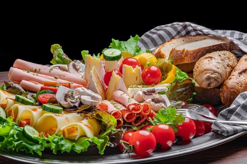A selection of cheeses and vegan sausages with pastries, vegetables and salad, appetisingly