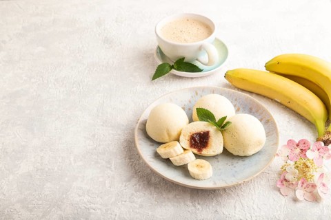 Japanese rice sweet buns mochi filled with jam and cup of coffee on a gray concrete background.