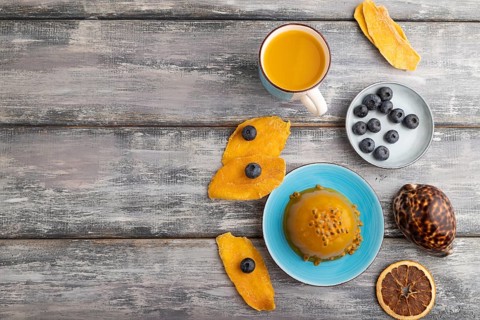 Mango and passion fruit jelly with blueberry on gray wooden background. top view, flat lay, copy