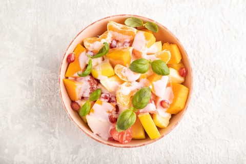 Vegetarian fruit salad of yogurt pumpkin, tangerine, pomegranate, grapefruit, basil microgreen