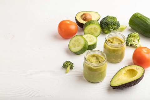 Baby puree with vegetable mix, broccoli, tomatoes, cucumber, avocado infant formula in glass jar on
