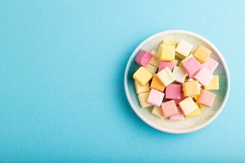 Various fruit jelly chewing candies on plate on blue pastel background. apple, banana, tangerine,