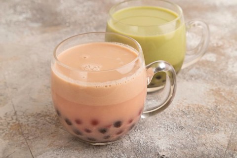 Bubble tea with pistachio and caramel in glass on brown concrete background. Healthy drink concept.