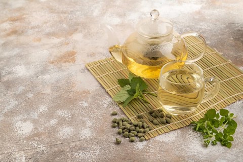 Green oolong tea with herbs in glass on brown concrete background. Healthy drink concept. Side