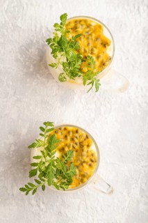 Yogurt with passionfruit and marigold microgreen in glass on gray concrete background. Top view,