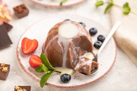 Chocolate jelly with strawberry, blueberry and milk cream sliced with spoon on gray concrete