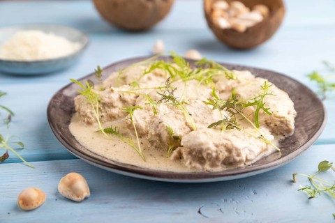 Stewed chicken fillets with coconut milk sauce and mizuna cabbage microgreen on blue wooden