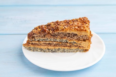 Walnut and hazelnut cake with caramel cream on blue wooden background. side view, close up