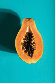 Ripe cut papaya on blue pastel background. Top view, flat lay, close up, hard light. Tropical,