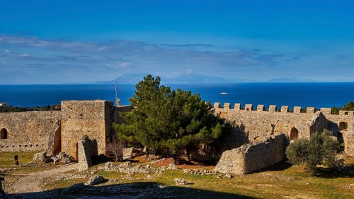 Sunny view of an old fortress with green trees and a blue sky with light clouds, Chlemoutsi, High