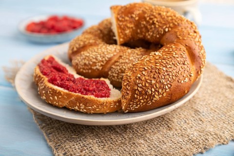 Homemade sweet bun with raspberry jam and cup of coffee on a blue wooden background and linen