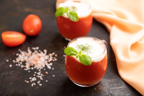 Tomato juice with basil, himalayan salt and sour cream in glass on a black concrete background with