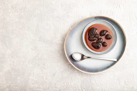 Pine cone jam on ceramic plate on gray concrete background. Top view, flat lay, copy space