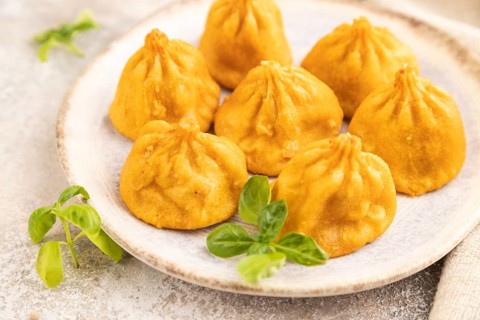 Fried manti dumplings with pepper, basil on gray concrete background and linen textile. Side view,