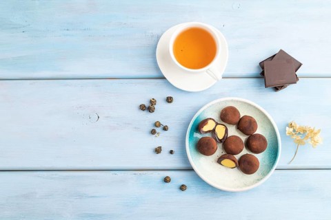 Japanese rice sweet buns chocolate mochi filled with cream and cup of green tea on blue wooden