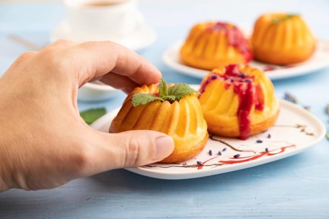 Semolina cheesecake with strawberry jam, lavender, with hand on blue wooden background. side view,