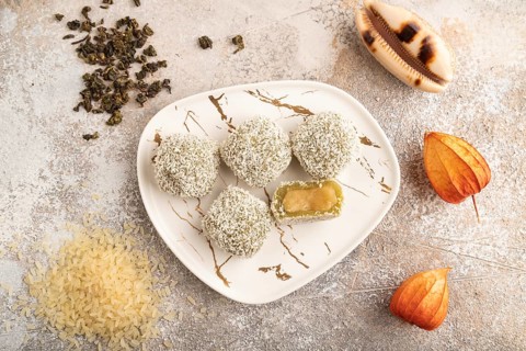 Japanese rice sweet buns mochi filled with pandan jam and cup of green tea on brown concrete