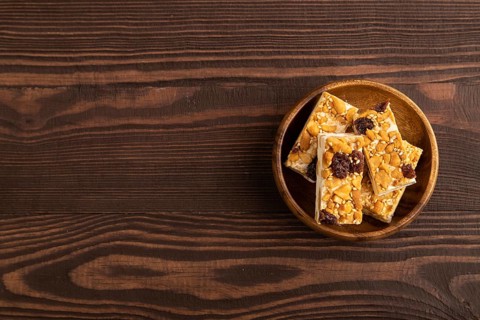 Traditional candy nougat with nuts and sesame on brown wooden background. top view, flat lay, copy