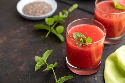 Watermelon juice with chia seeds and mint in glass on a black concrete background with green