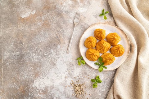 Fried manti dumplings with pepper, basil on gray concrete background and linen textile. Top view,