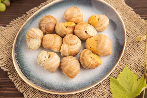 Grape (Burgundy) snails with butter and cheese on brown wooden background and linen textile. Side