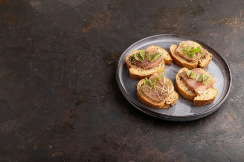 Bread sandwiches with jerky salted meat, sorrel and cilantro microgreen on black concrete