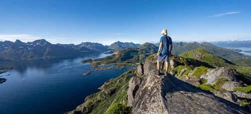 Mountaineer on the summit of Dronningsvarden or Stortinden, mountains and fjord Raftsund,
