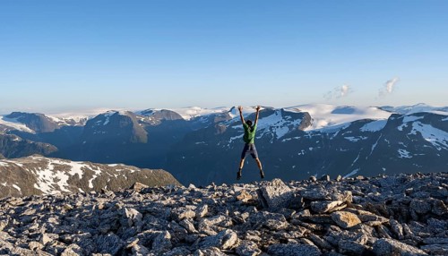 Mountain panorama with mountain peaks and glacier Jostedalsbreen, mountaineer stretches his arms in