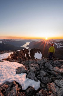 View of mountains and fjord Faleidfjorden, sun star at sunset, mountaineer at the summit of Skala,