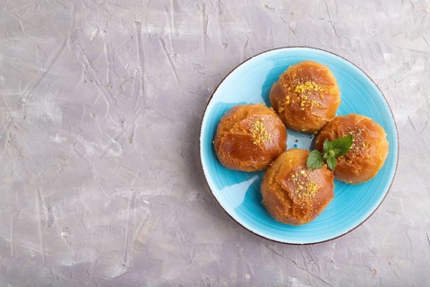 Homemade traditional turkish dessert sekerpare with almonds and honey on gray concrete background.