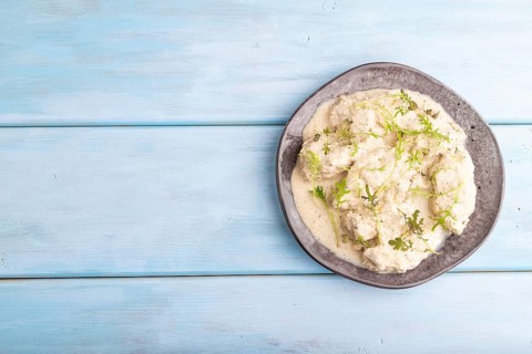 Stewed chicken fillets with coconut milk sauce and mizuna cabbage microgreen on blue wooden